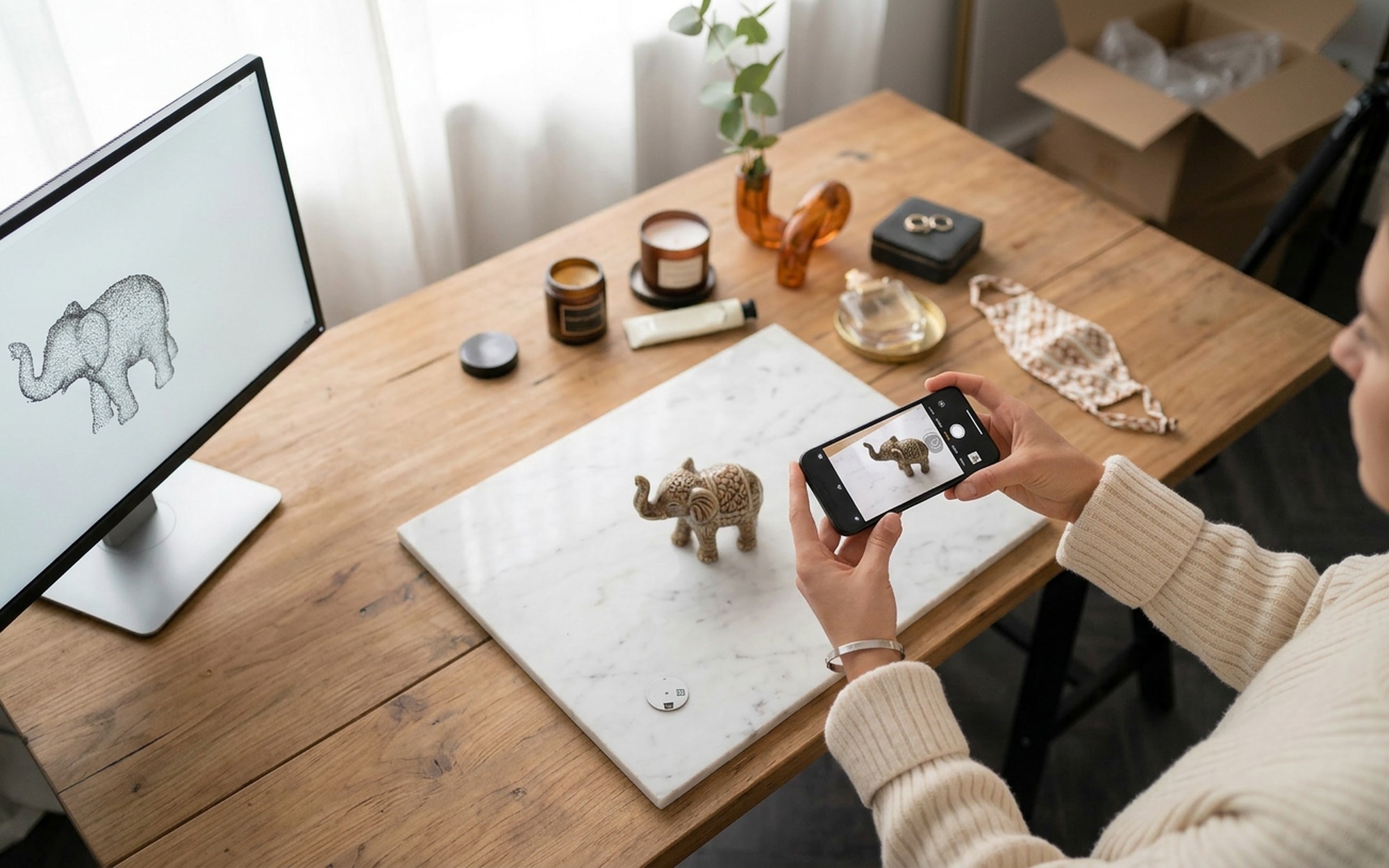 Close-up of hands holding a smartphone to photograph a small ceramic figure on a wooden desk for photogrammetry 3D scanning