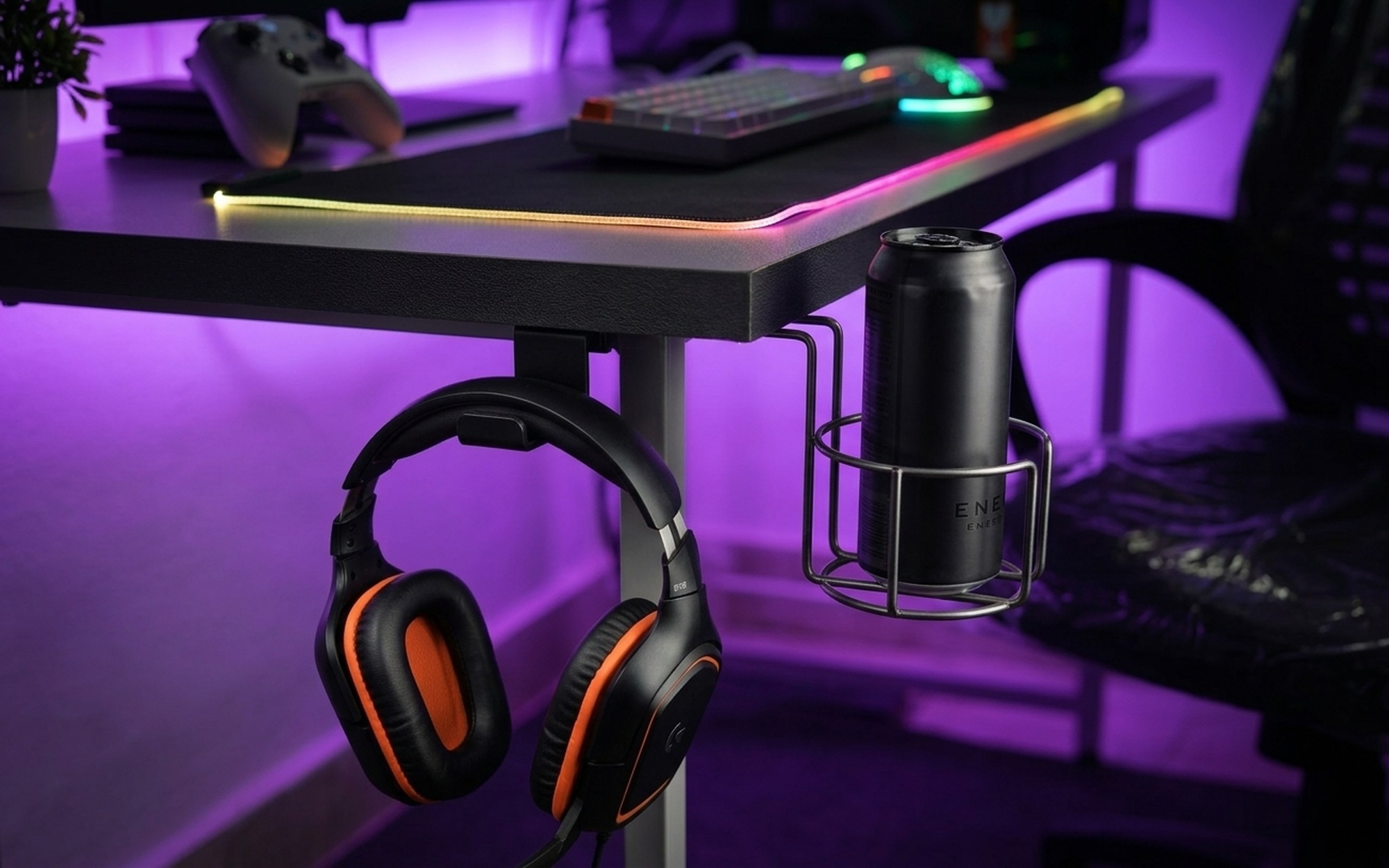 Close-up of gaming desk accessories including headphone hook cup holder cable management grommets and RGB LED strip lighting
