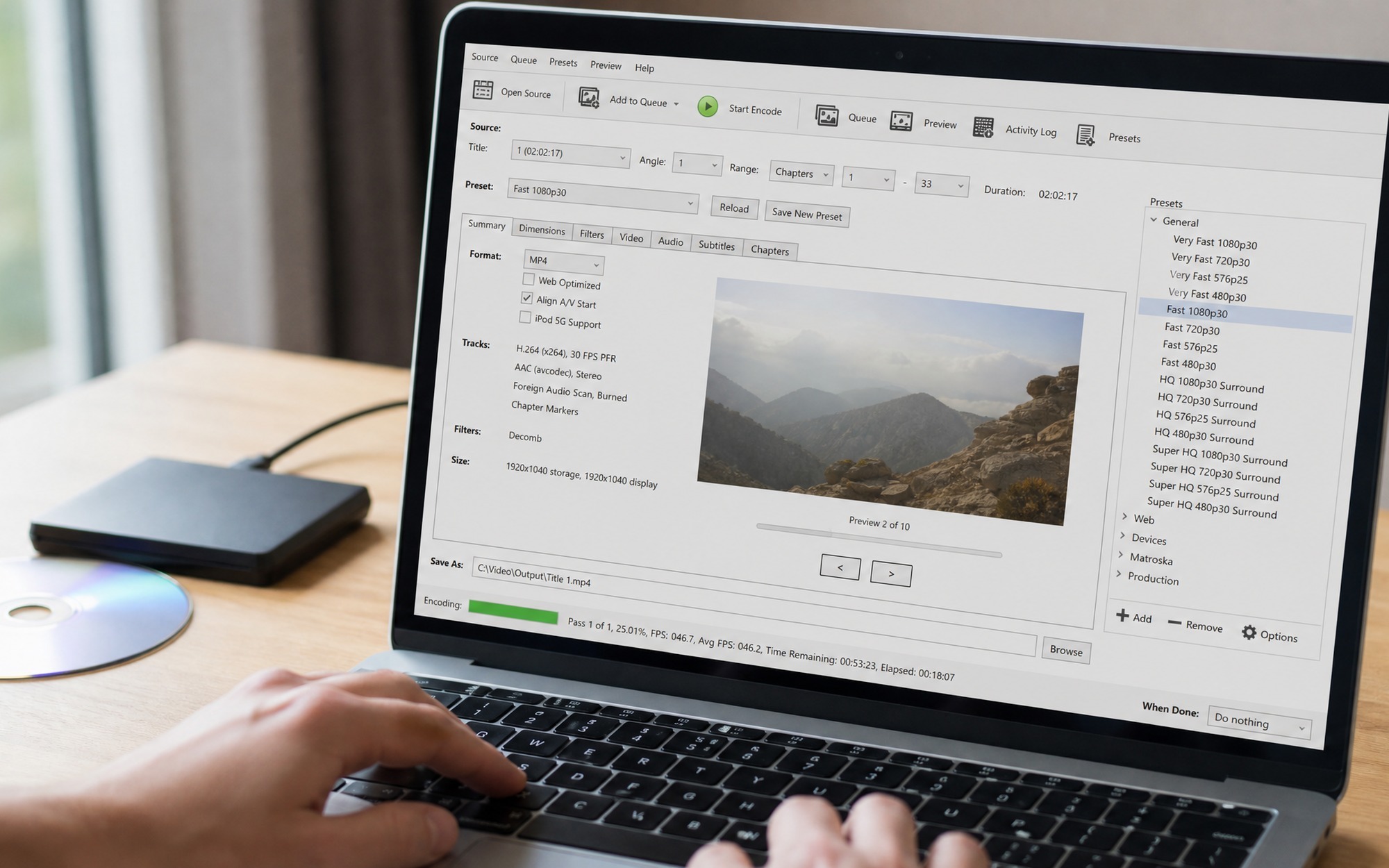 close-up hands holding DVD disc near laptop keyboard with HandBrake DVD to MP4 conversion settings visible on screen