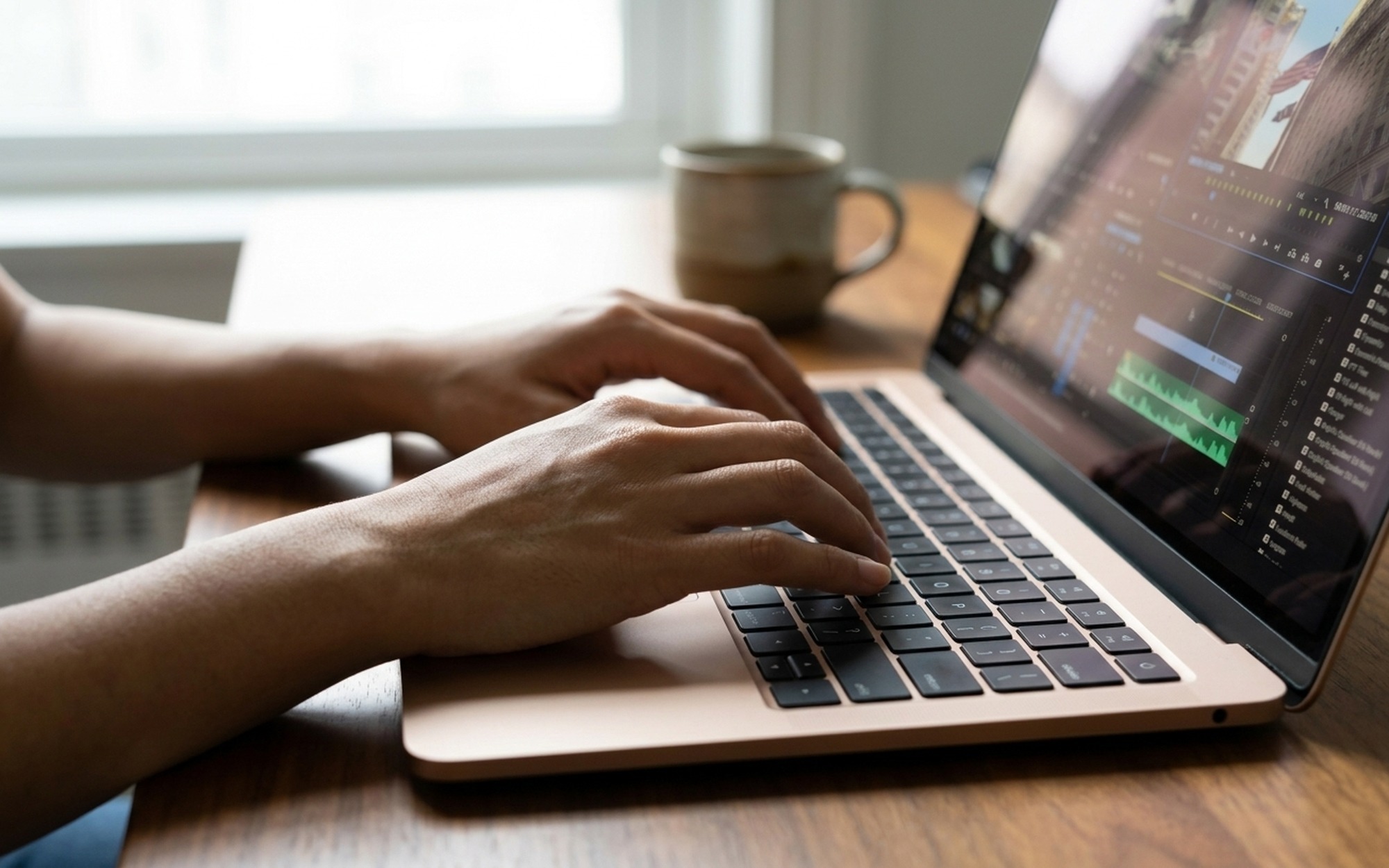 Close-up of hands on a laptop keyboard with a video converter software interface open, format selection dropdown visible on screen