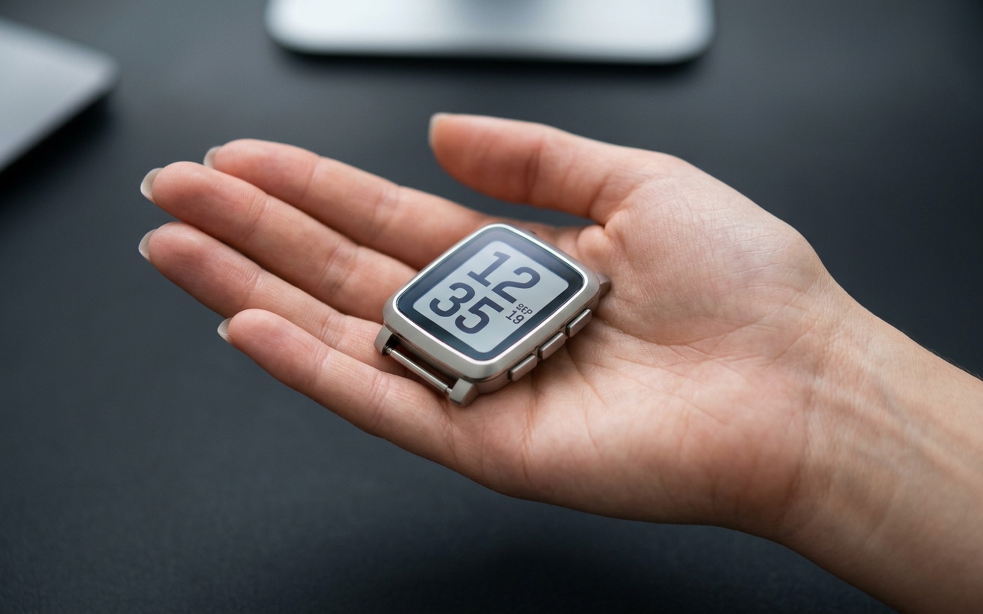 Pebble Time 2 smartwatch on wrist showing 64-color e-paper display with watchface complications and four side buttons