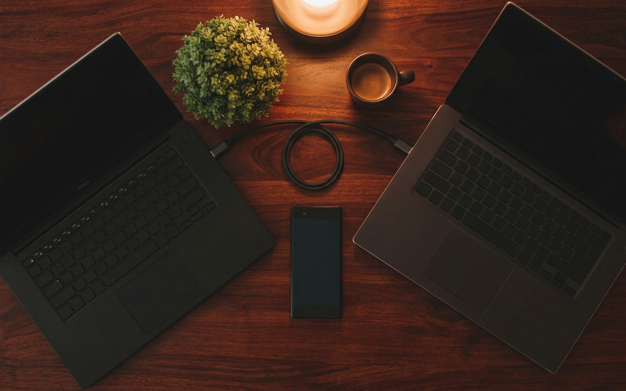 Man at a desk comparing free and paid phone transfer methods with iPhone and Samsung Galaxy placed side by side