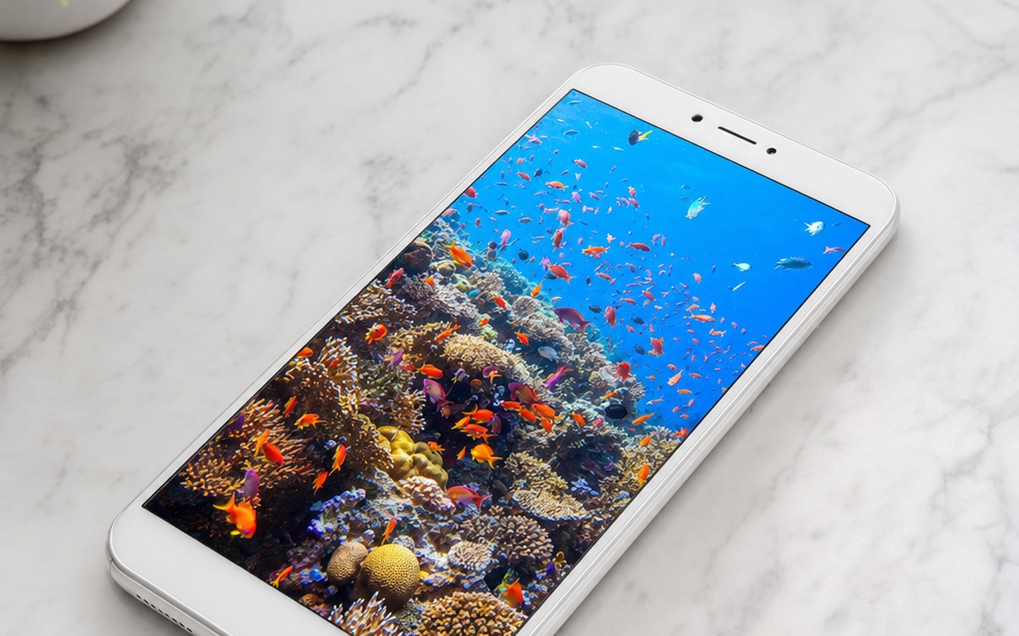 Xiaomi 17 Max white smartphone lying face-up on marble surface displaying vibrant AMOLED screen with tropical reef scene