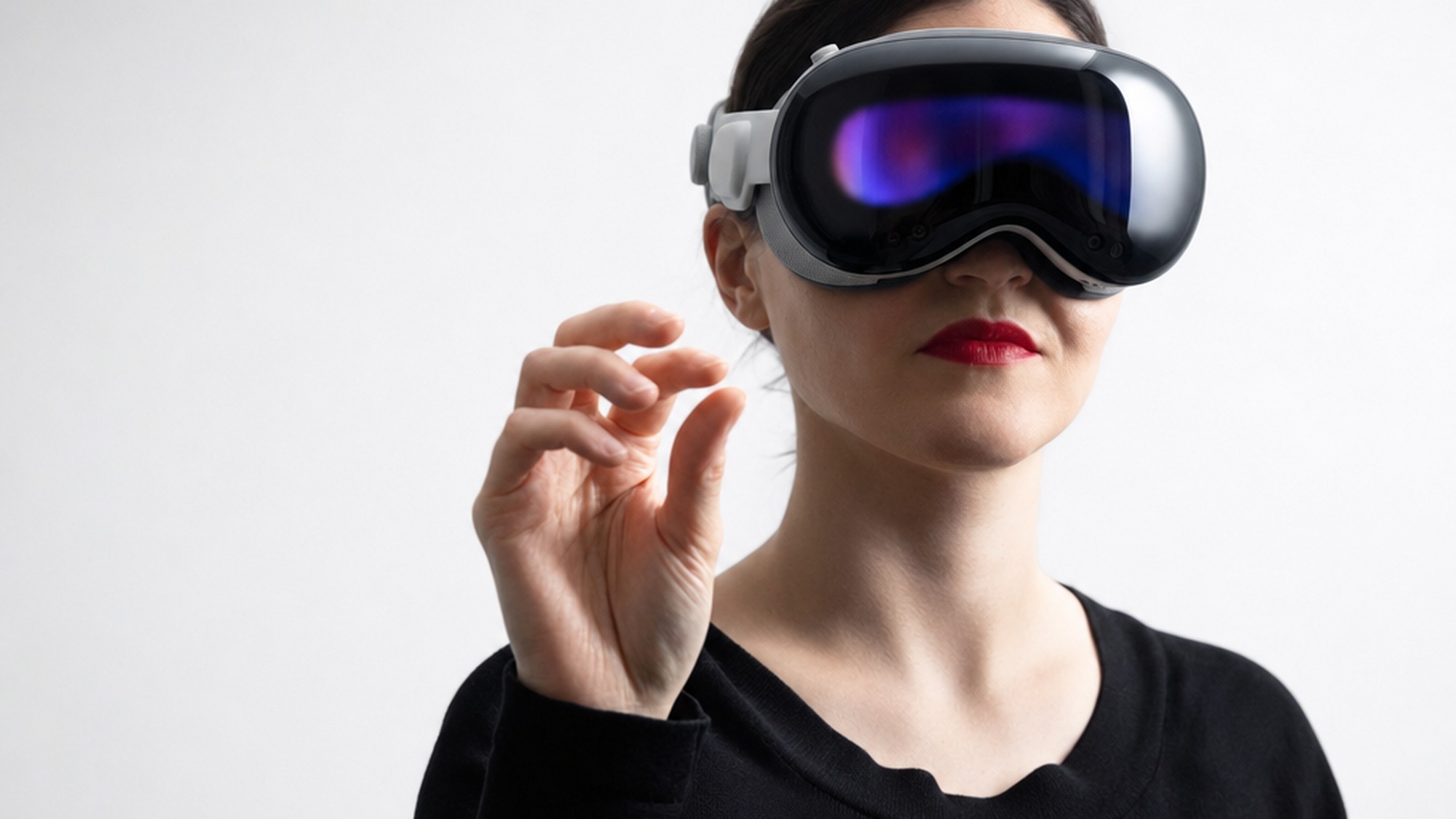 A person wearing a sleek mixed reality headset with a curved visor making a pinch gesture, illustrating how a headset differs from glasses.