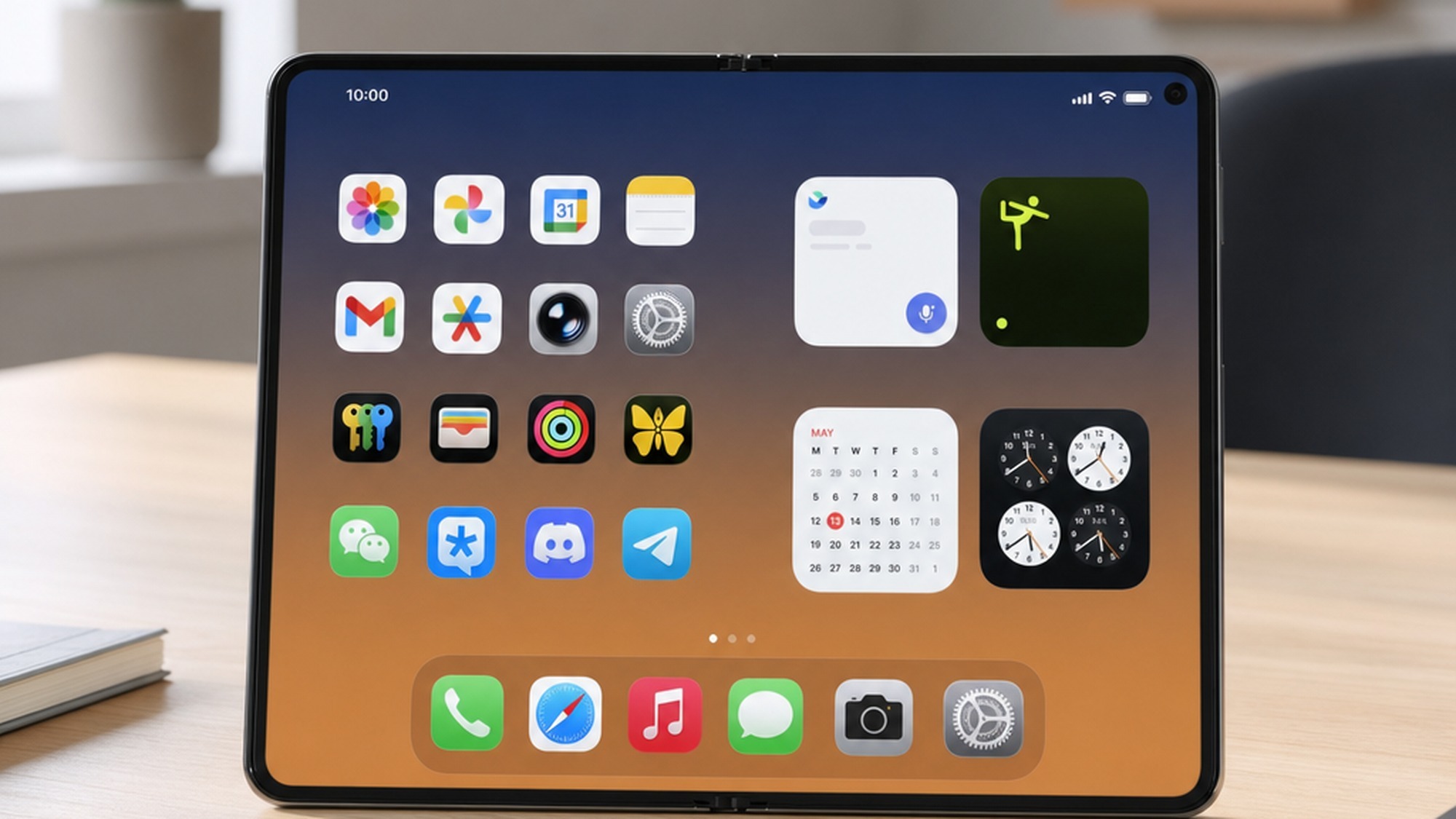 A foldable iPhone Ultra concept opened flat on a desk showing the wide iOS 27 landscape home screen layout
