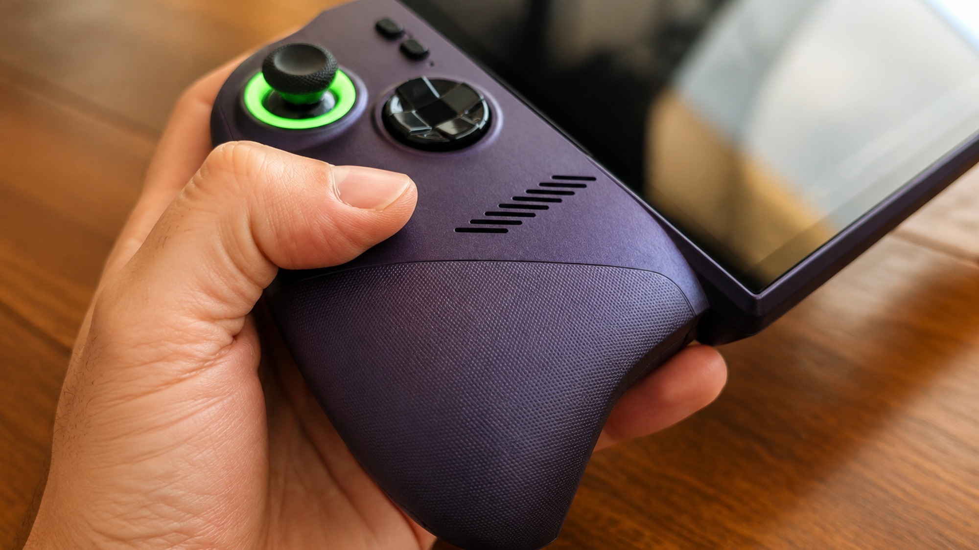 Close up of a hand gripping the textured ergonomic grip and joystick of the MSI Claw 8 EX AI+ gaming handheld PC